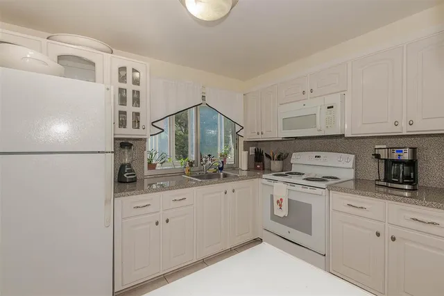 a kitchen with white cabinets and white appliances