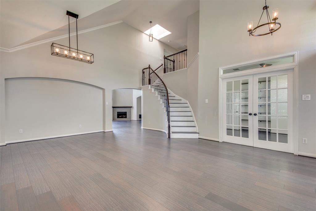 a view of an empty room with wooden floor and a ceiling fan