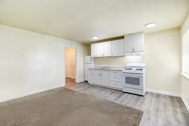 a kitchen with granite countertop white cabinets and a sink