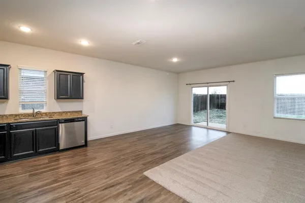 an empty room with wooden floor and stainless steel appliances