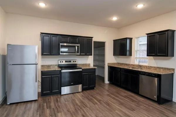 a large kitchen with stainless steel appliances and wooden cabinets