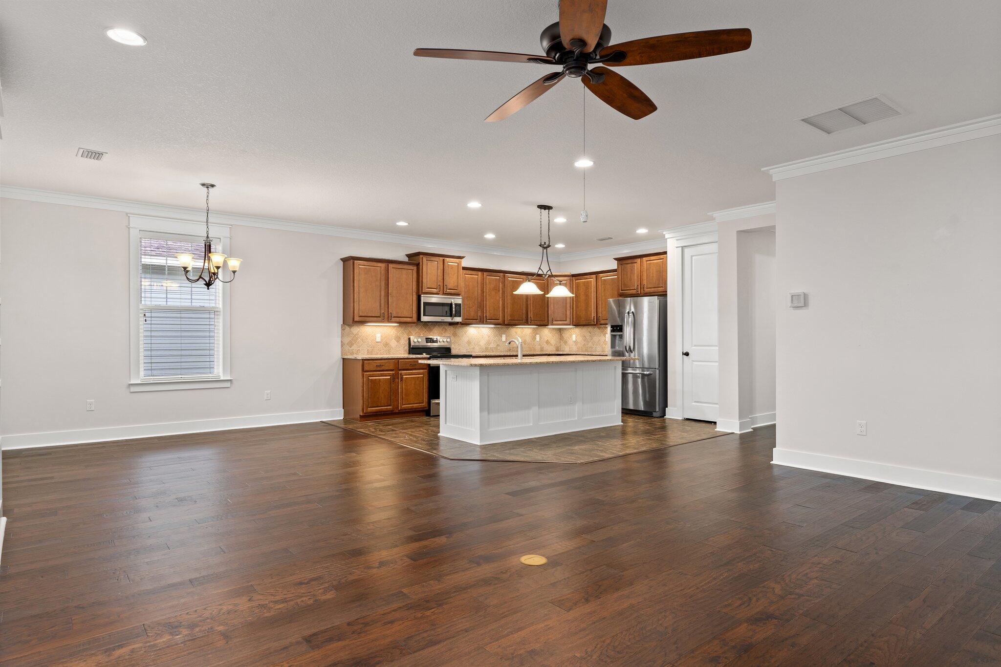 112 Blue Sage Road Panama City Beach, FL 32413 - Photo 21 of 46 a view of an empty room and kitchen with window wooden floor and a ceiling fan