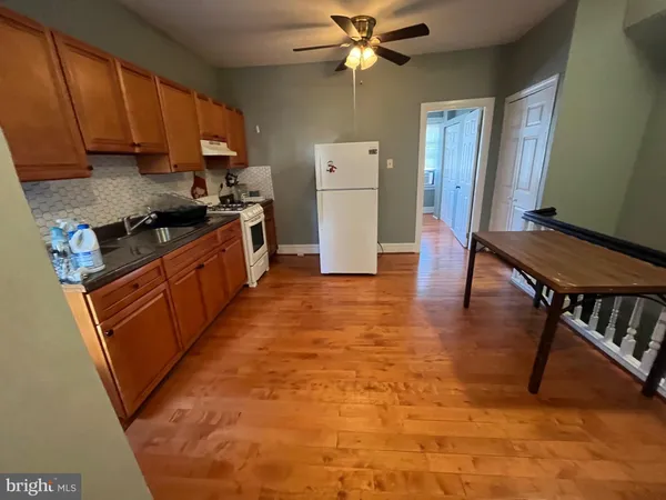 a kitchen with granite countertop a stove a sink dishwasher and a refrigerator with wooden floor