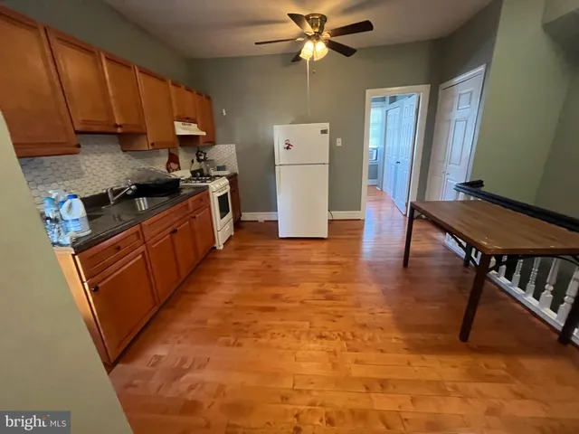 a kitchen with granite countertop a stove a sink dishwasher and a refrigerator with wooden floor