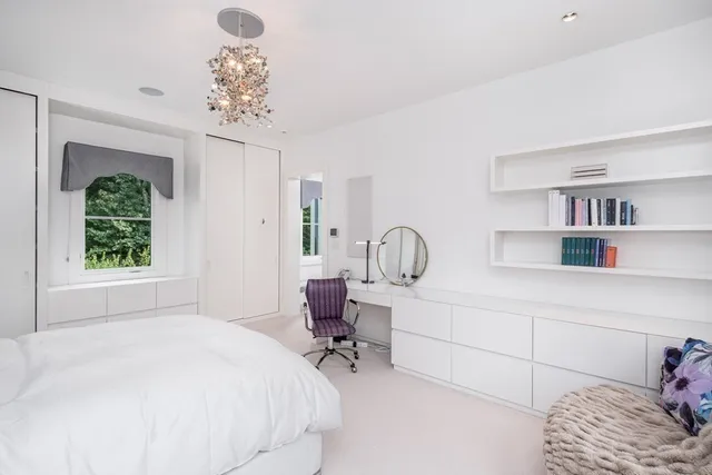 a bedroom with a bed a chandelier and a bookshelf with wooden floor