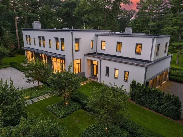 a view of a white house with a big yard plants and large trees