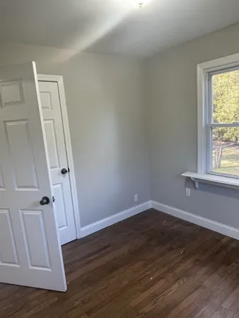 an empty room with wooden floor and window