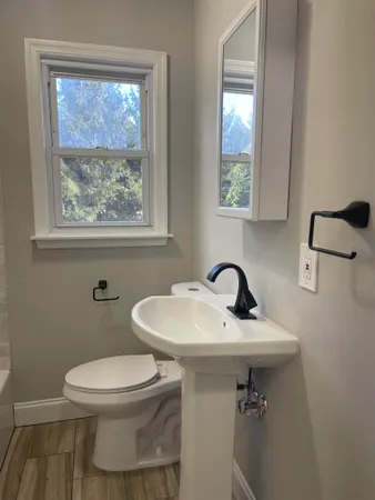a bathroom with a sink a toilet and a window