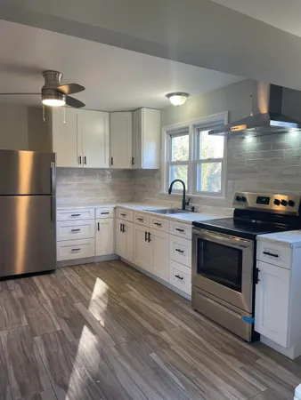 a kitchen with a sink a stove a refrigerator and white cabinets