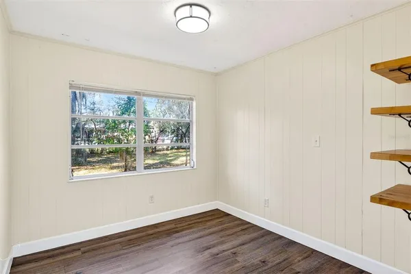 a view of an empty room with wooden floor and a window