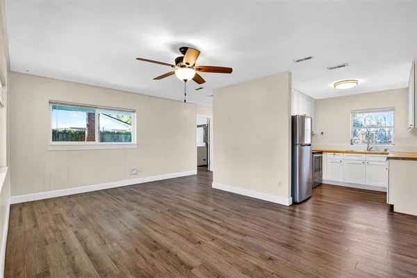 a view of a kitchen with a kitchen island wooden floors appliances and a window