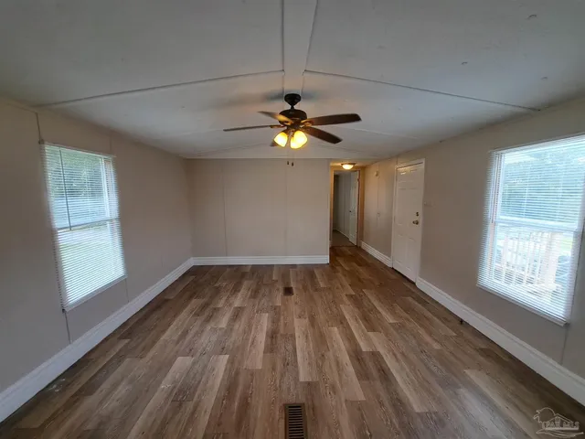 a view of empty room with wooden floor and fan
