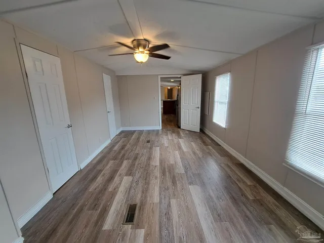 a view of empty room with wooden floor and fan