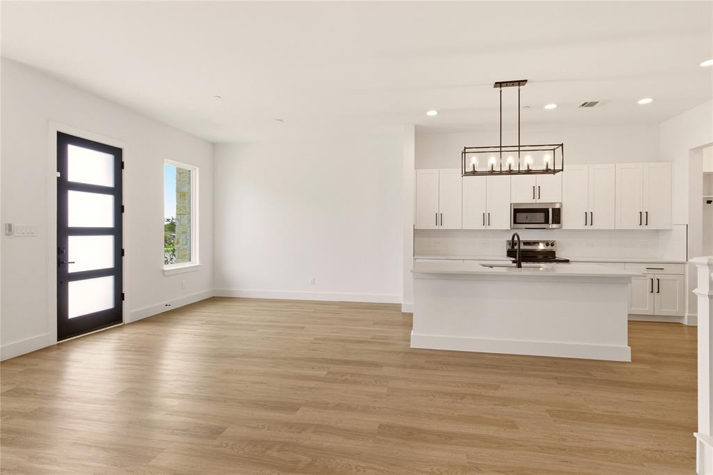 8909 Lowell Street Rowlett, TX 75089 - Photo 4 of 25 Kitchen featuring white cabinets, light wood-style flooring, stainless steel microwave, hanging light fixtures, and electric stove
