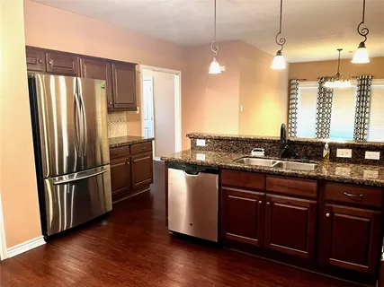 a kitchen with stainless steel appliances granite countertop a refrigerator a sink and a stove