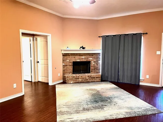 an empty room with wooden floor fireplace and windows