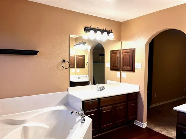 a bathroom with a double vanity sink mirror and bathtub