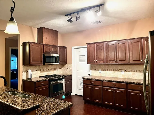 a kitchen with stainless steel appliances granite countertop a stove refrigerator and a microwave oven