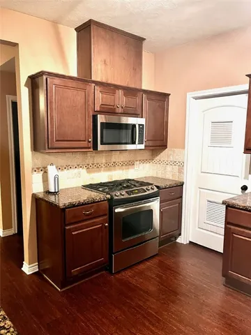 a kitchen with kitchen island granite countertop wooden cabinets and stainless steel appliances