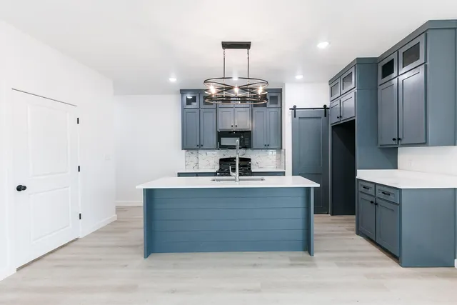 a kitchen with kitchen island stainless steel appliances a chandelier and wooden floor