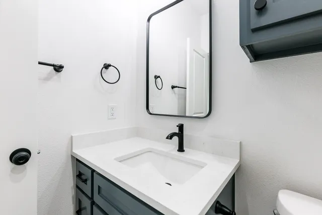 a bathroom with a sink and mirror with toilet