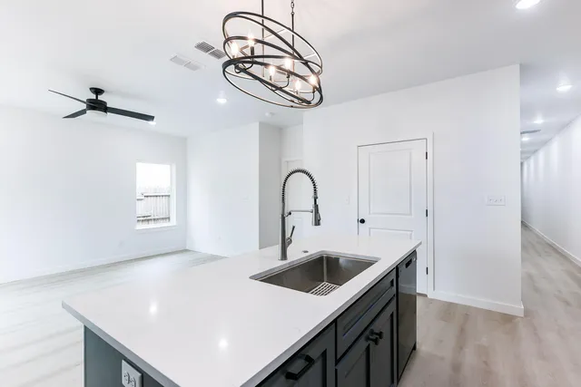 a kitchen with a sink a kitchen island with stainless steel appliances wooden floor and cabinets