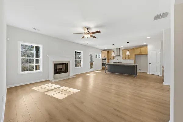 a view of kitchen and empty room with wooden floor and a fireplace