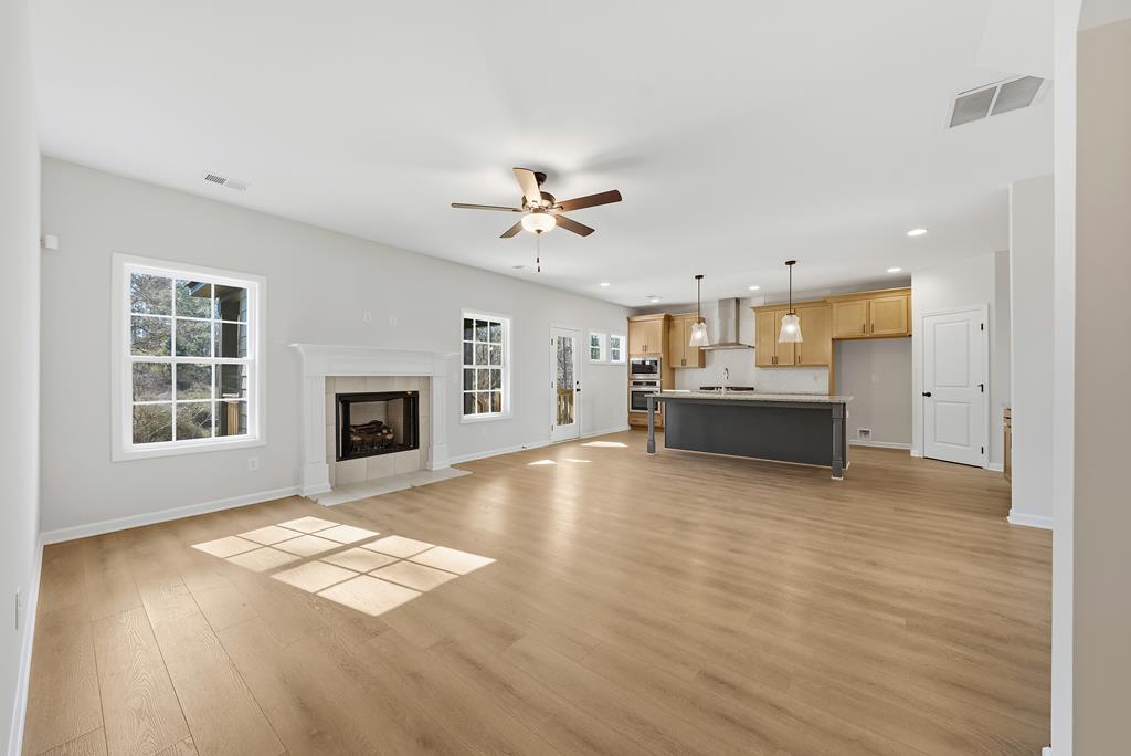 1304 McAlpine Ridge Auburn, AL 36830 - Photo 12 of 34 a view of kitchen and empty room with wooden floor and a fireplace