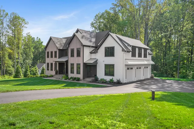 a view of a yard in front of a house with plants and large trees