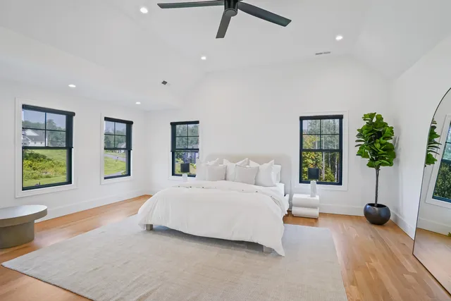 a bedroom with a large bed a potted plant and a large window