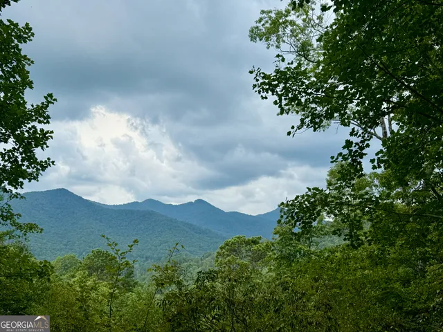 an aerial view of a house with a yard and mountains in the background