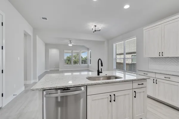 a kitchen with kitchen island granite countertop a sink cabinets and window