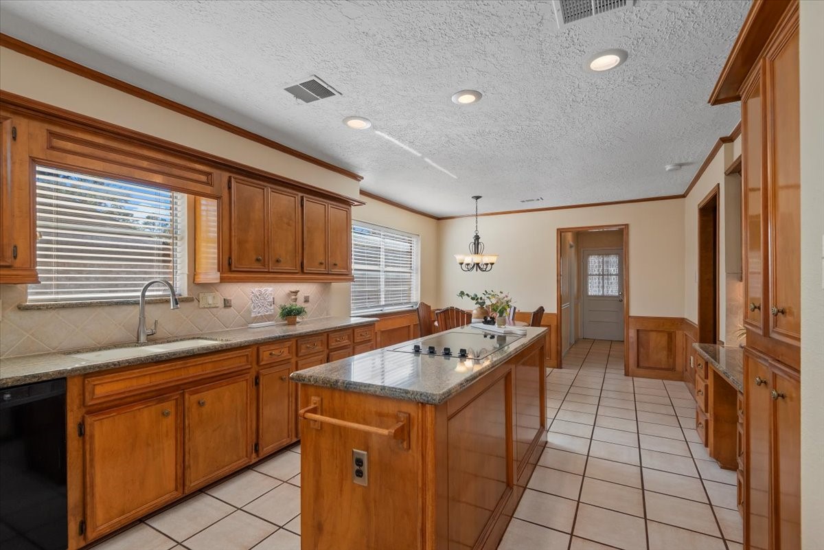 16707 Rugby Court Spring, TX 77379 - Photo 11 of 48 This large kitchen offers extensive wood cabinetry, granite work surfaces, and a center island with built-in cooktop.