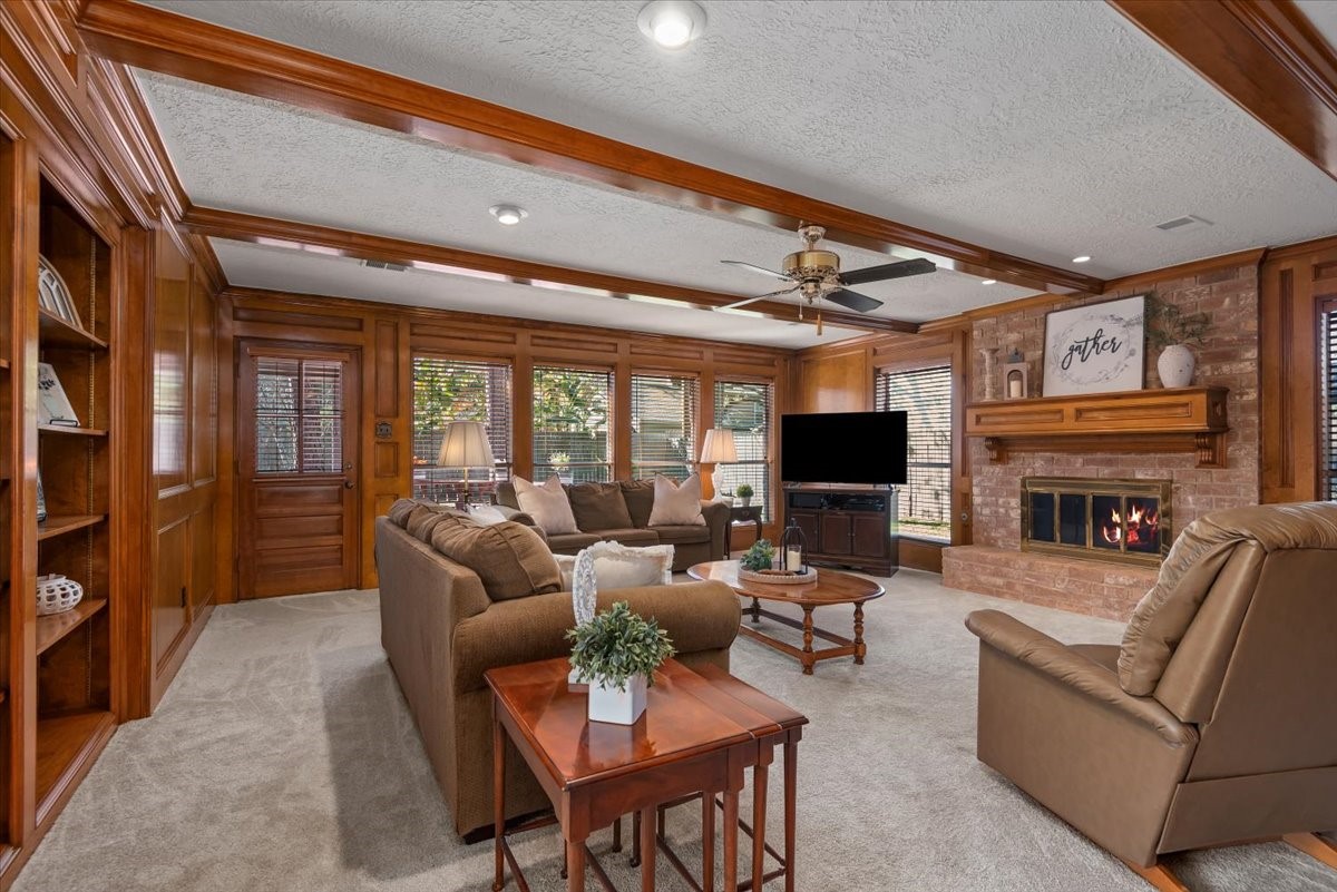 16707 Rugby Court Spring, TX 77379 - Photo 18 of 48 The living room is a spacious gathering area featuring wood-paneled walls, exposed ceiling beams, and large windows. The exterior door will lead you to the covered back patio area.