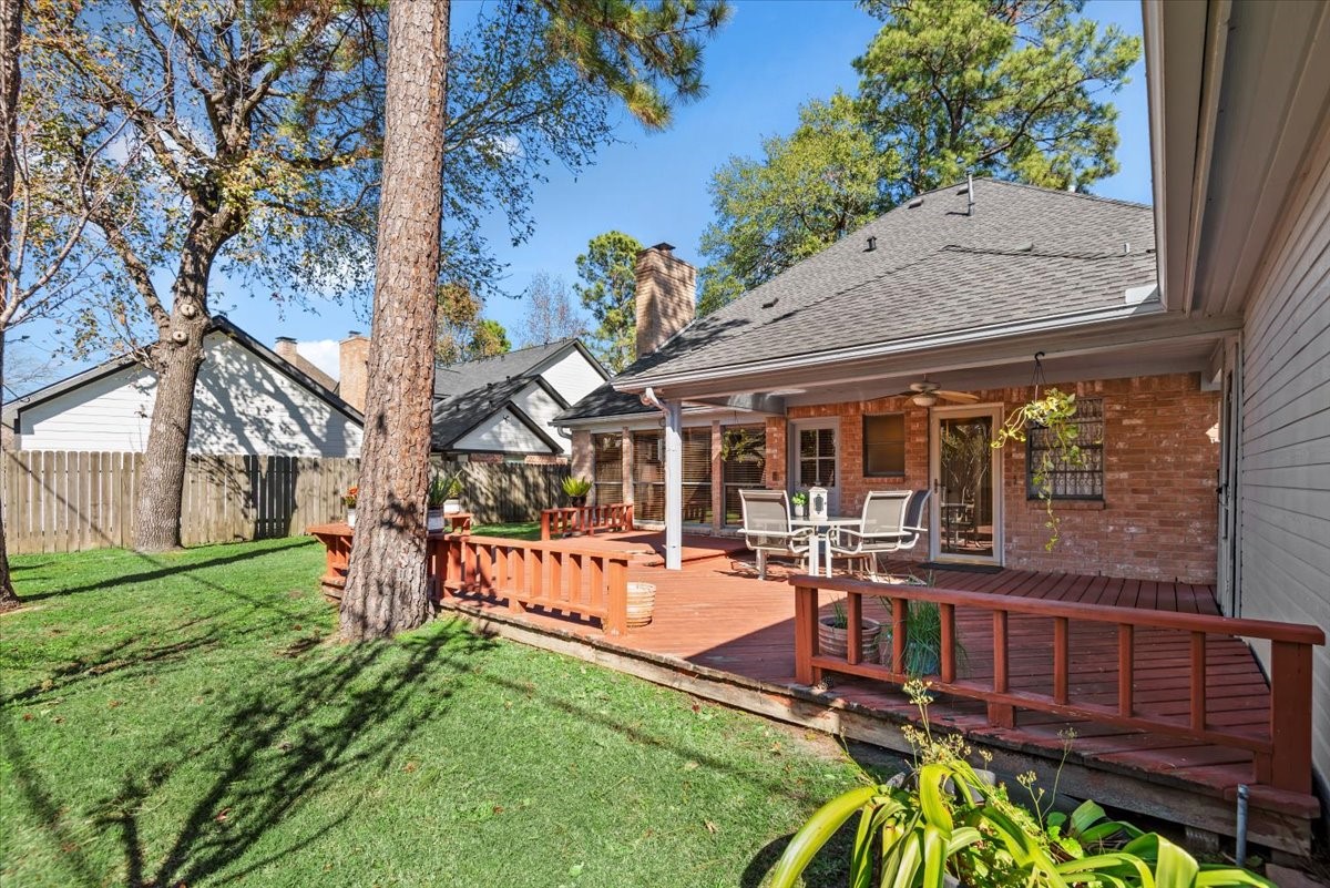 16707 Rugby Court Spring, TX 77379 - Photo 37 of 48 This backyard oasis features a raised wood deck with railing, covered patio area, and ceiling fan. The fully fenced yard with mature trees provides a private space to relax and enjoy.