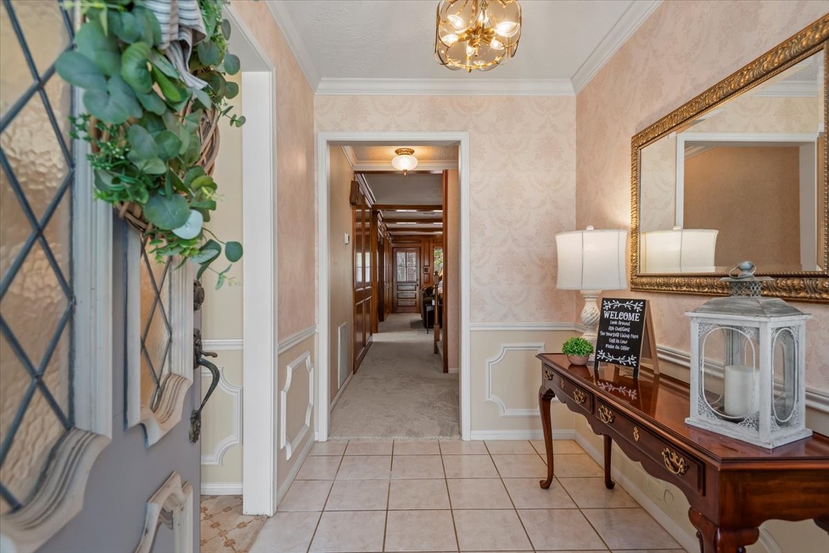 16707 Rugby Court Spring, TX 77379 - Photo 5 of 48 Entry foyer featuring tile flooring, chair rail detailing, and overhead lighting. Hallway provides access to interior living areas, with carpeted flooring extending into adjacent rooms.