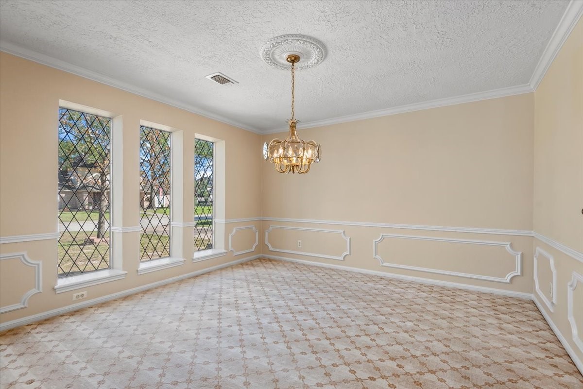 16707 Rugby Court Spring, TX 77379 - Photo 7 of 48 The formal dining room is a beautiful space with patterned carpet, crown molding, and a stunning chandelier. Three front-facing windows allow daylight to enter, while the wall accents add even more charm to this room.