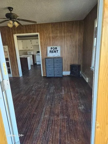 a view of empty room with wooden floor and fan