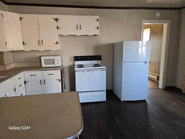 a kitchen with granite countertop white cabinets and white appliances