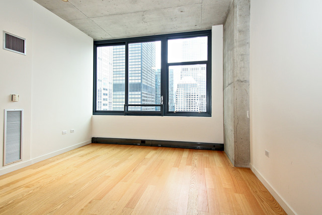 235 West Van Buren Street, Unit 3420 Chicago, IL 60607 - Photo 8 of 18 an empty room with wooden floor and windows