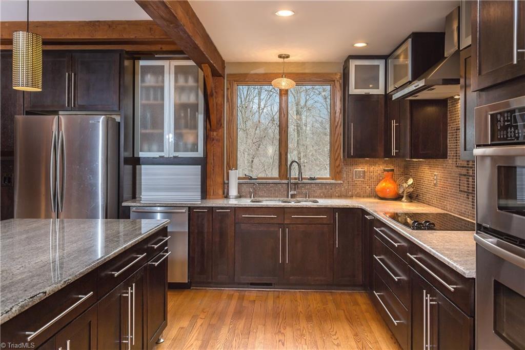 6111 Meadow Bluff Lane Oak Ridge, NC 27310 - Photo 11 of 30 Nothing rustic about the kitchen! Sleek and modern in a simple design. Granite countertops with glass tile backsplash. Stainless appliances including a large range hood. Window overlooks rear yard and pool.