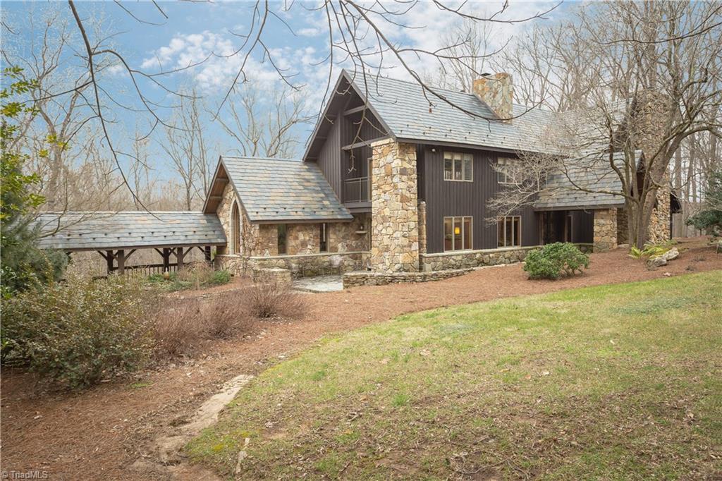 6111 Meadow Bluff Lane Oak Ridge, NC 27310 - Photo 3 of 30 The exterior is a combination of stone and wood with casement and gothic fixed windows. The massive chimneys are stone with one face a rock climbing wall. Stone landscaping walls and paths meander throughout the yard.
