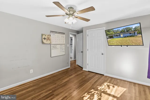 an empty room with wooden floor and ceiling fan