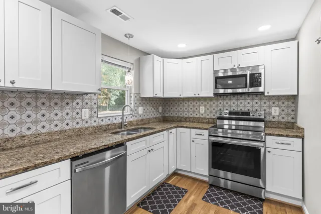a kitchen with stainless steel appliances granite countertop a stove sink and microwave