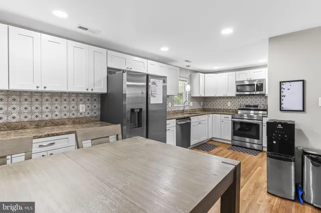a kitchen with stainless steel appliances wooden floor sink stove and cabinets