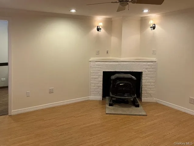 a view of an empty room with wooden floor and a fireplace