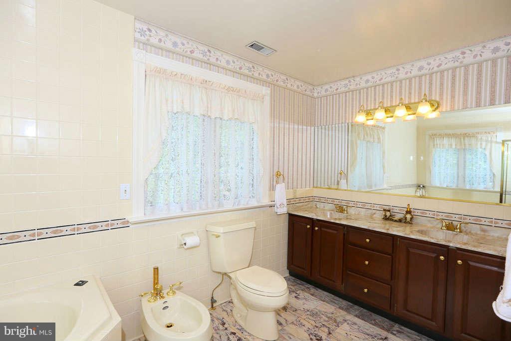 12530 Falls Road Potomac, MD 20854 - Photo 15 of 27 a bathroom with a granite countertop toilet a sink and a mirror