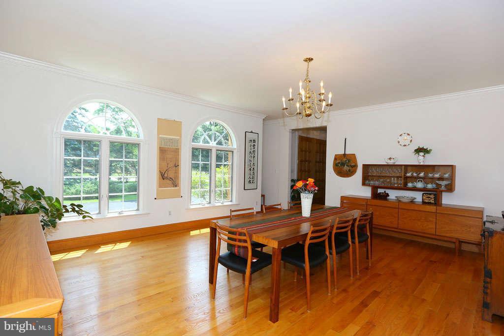 12530 Falls Road Potomac, MD 20854 - Photo 7 of 27 a dining room with wooden floor a chandelier a wooden table and chairs
