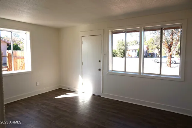 a view of an empty room with wooden floor and a window