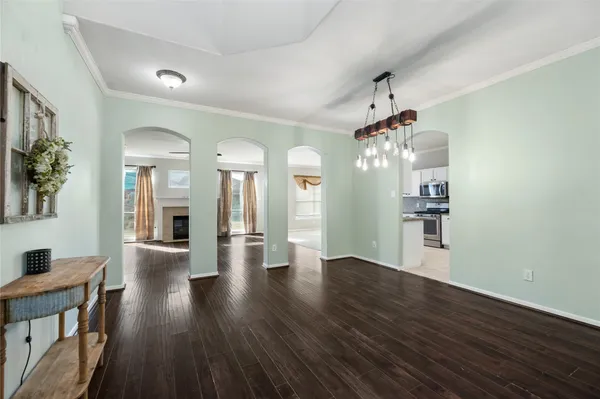 a view of a hallway with wooden floor and a kitchen